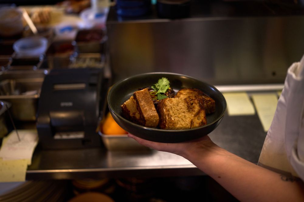 Bowl of braised meat dish garnished with herbs in warm lighting.