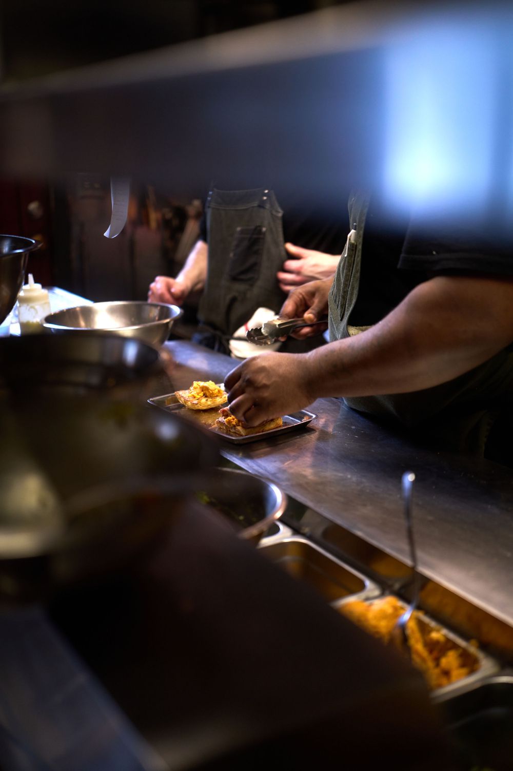 Chef plating food at busy restaurant service line.