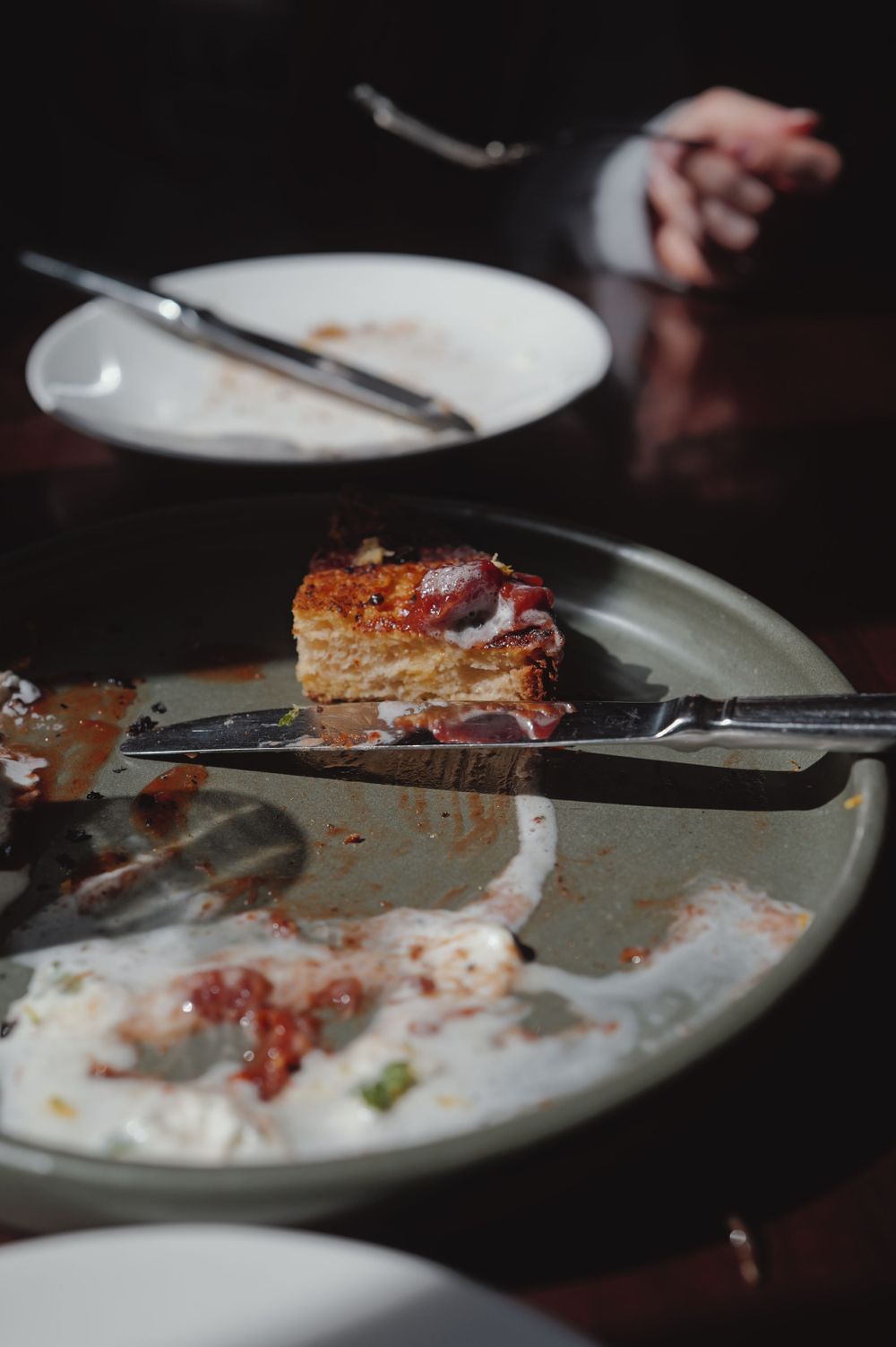 Partially eaten lasagna slice on white plate with sauce remnants.