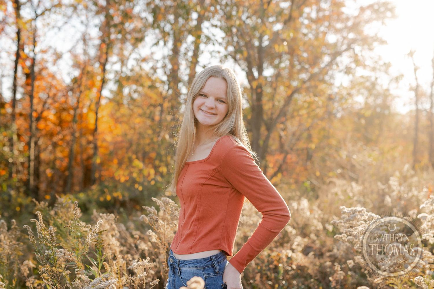 Autumn portrait with golden light and vibrant fall foliage in the background.