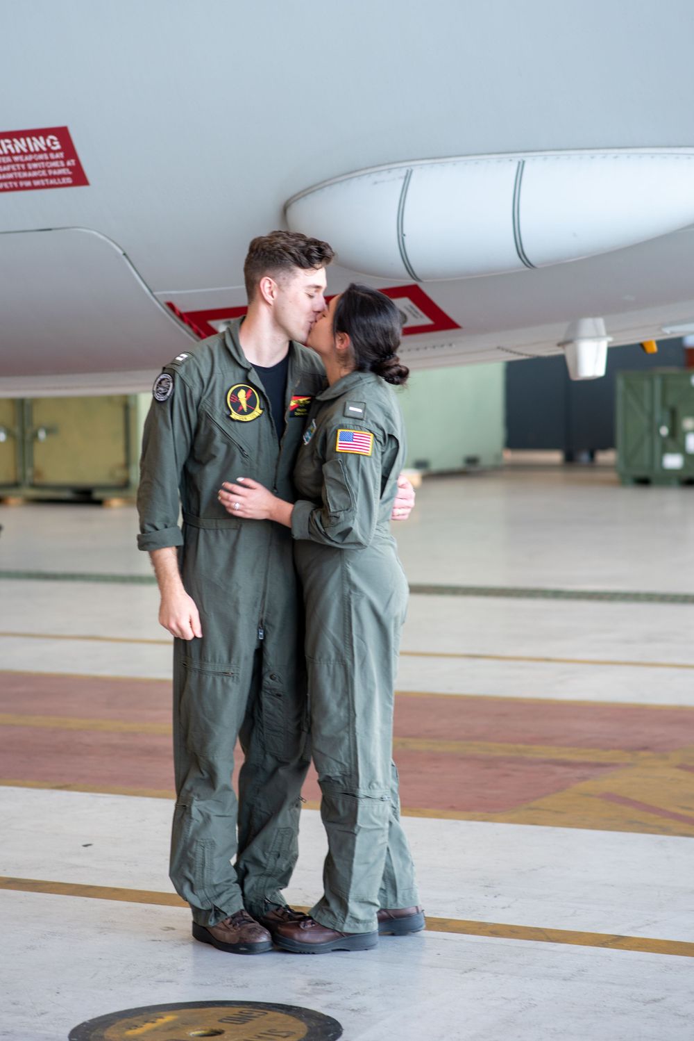 A military couple embraces in the hangar bay of the P8 Poseidon in Jacksonville Florida.
