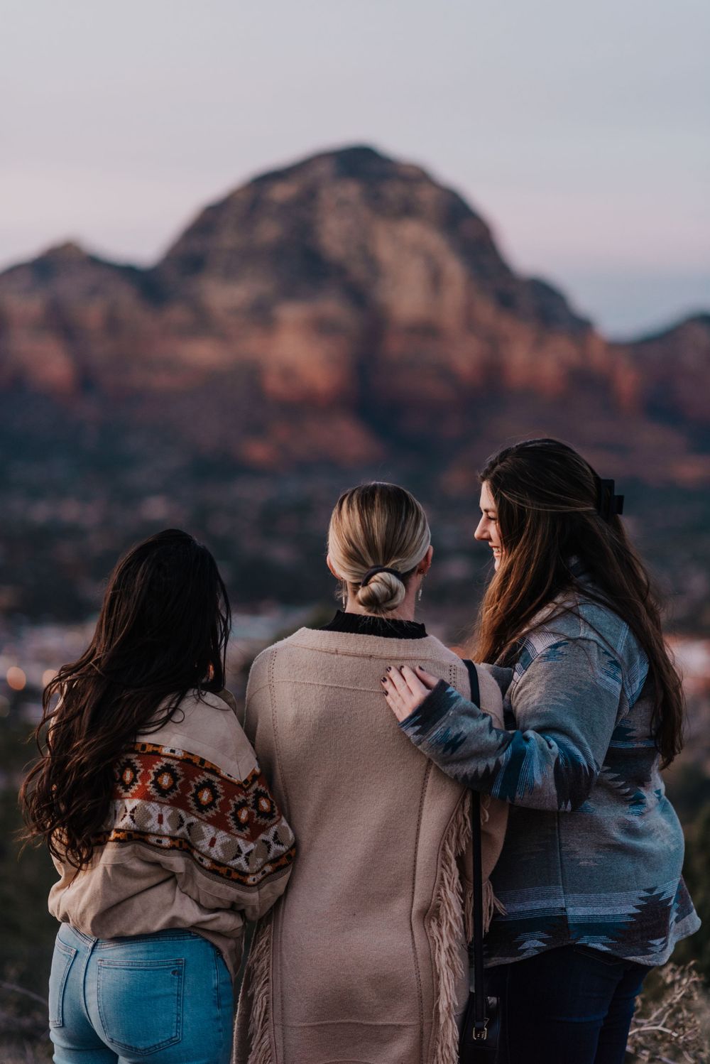three friends embrace beneath the red rocks of Sedona Arizona.