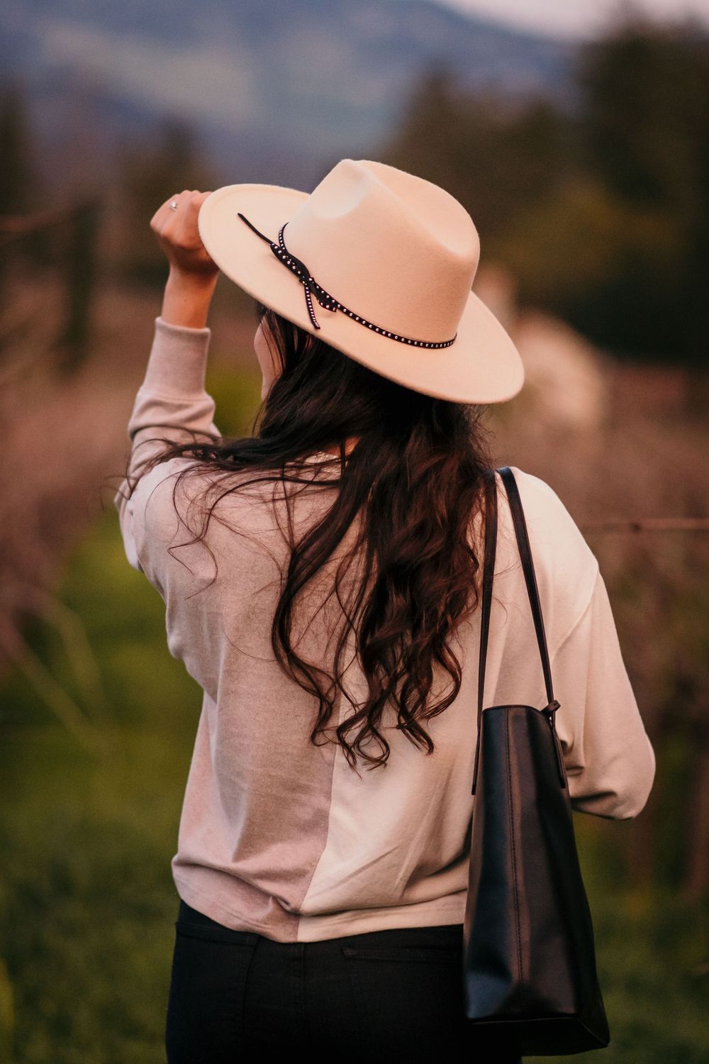 a portrait of a girl in a wide brimmed hat strolling through the vineyards in napa valley.