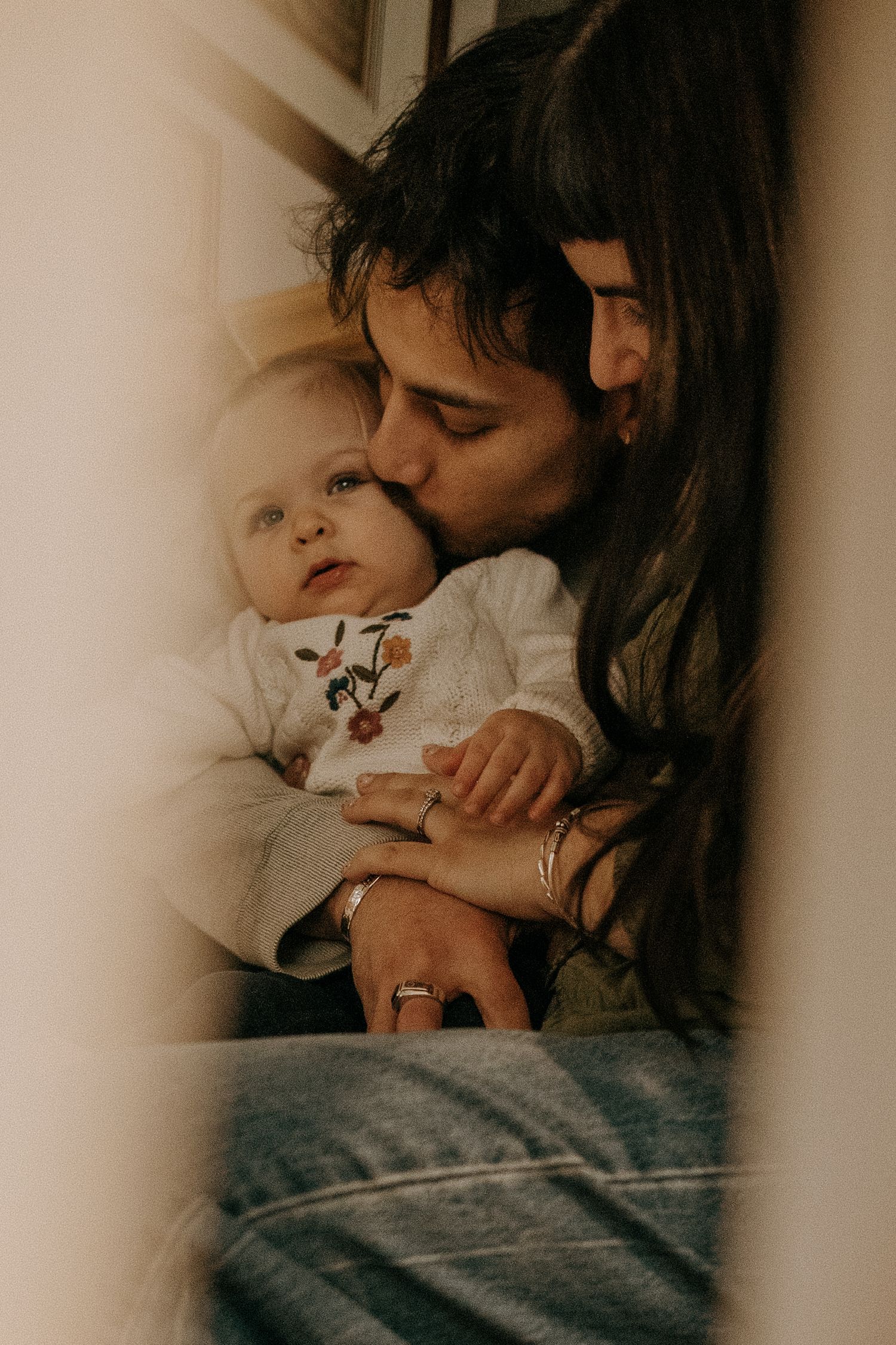 A tender moment between parent and baby in warm vintage tones as they share an intimate embrace.