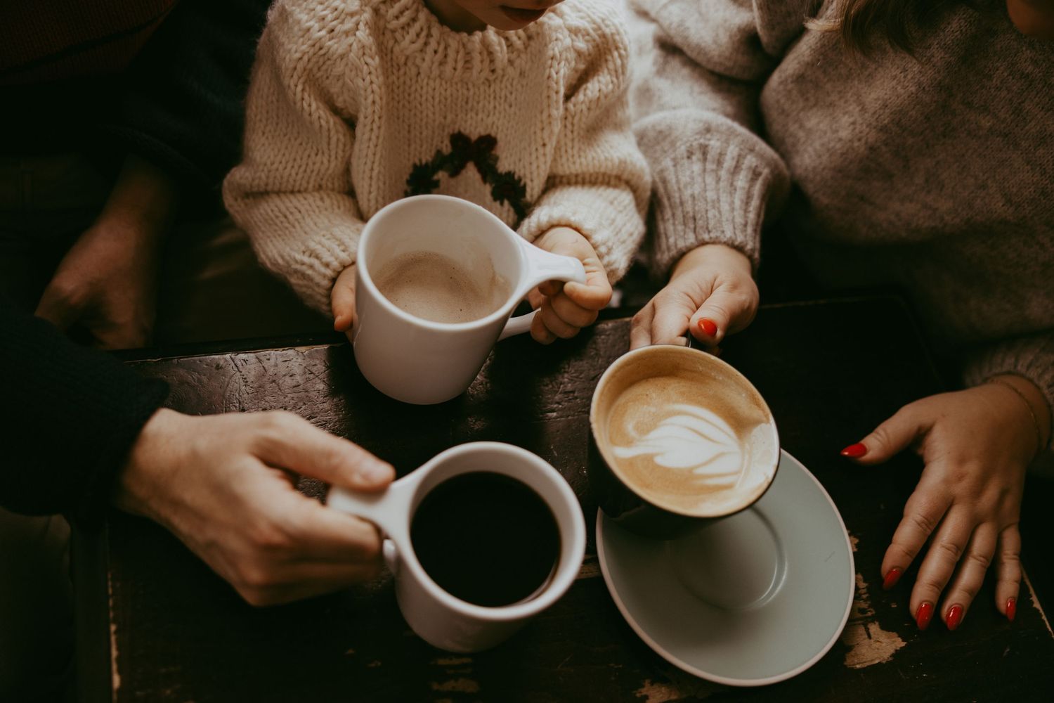 Hands holding various coffee cups with latte art and espresso drinks in a sequence of artistic preparation shots.