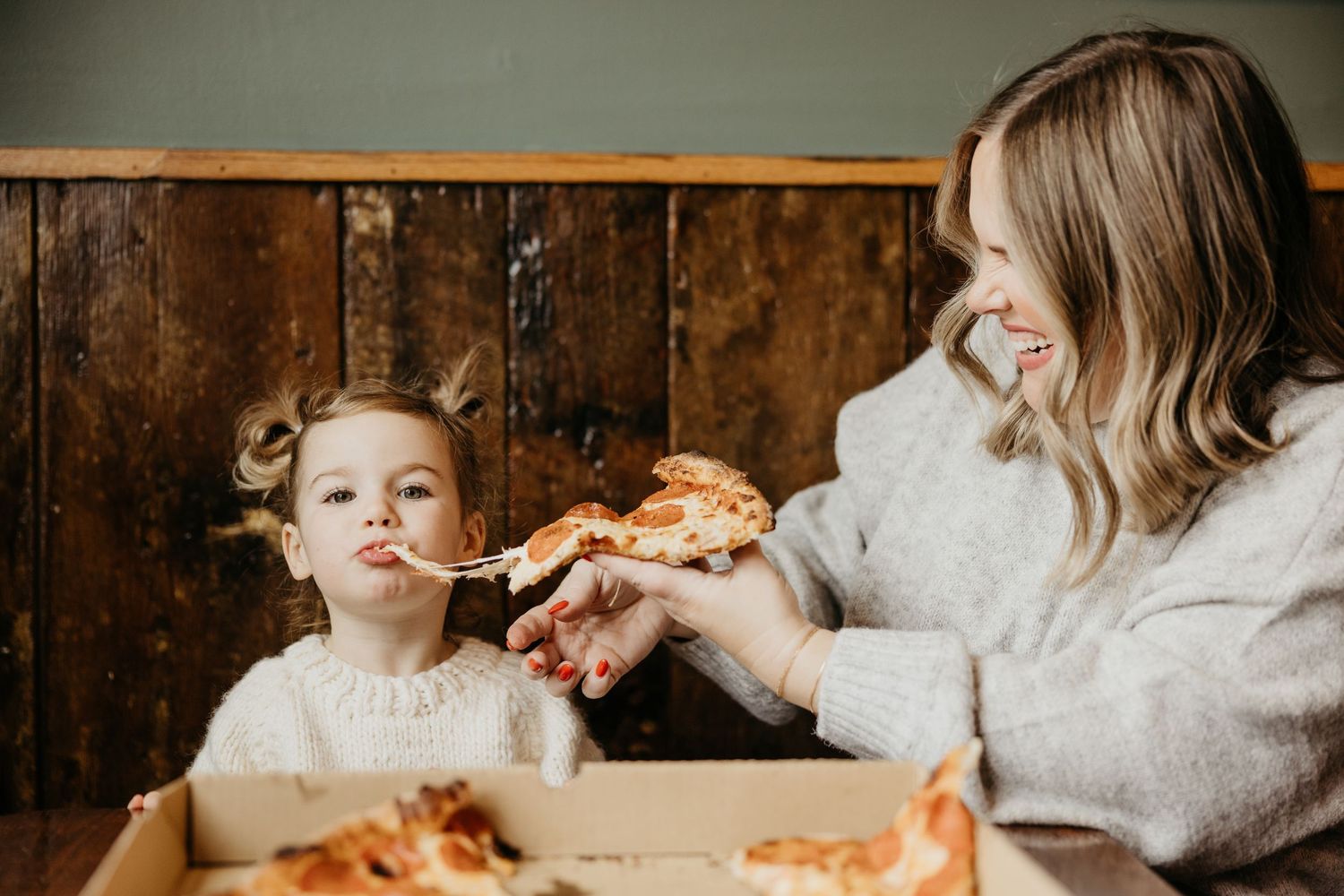 A sequence of photos showing someone taking bites of a slice of pizza while wearing a gray sweater.