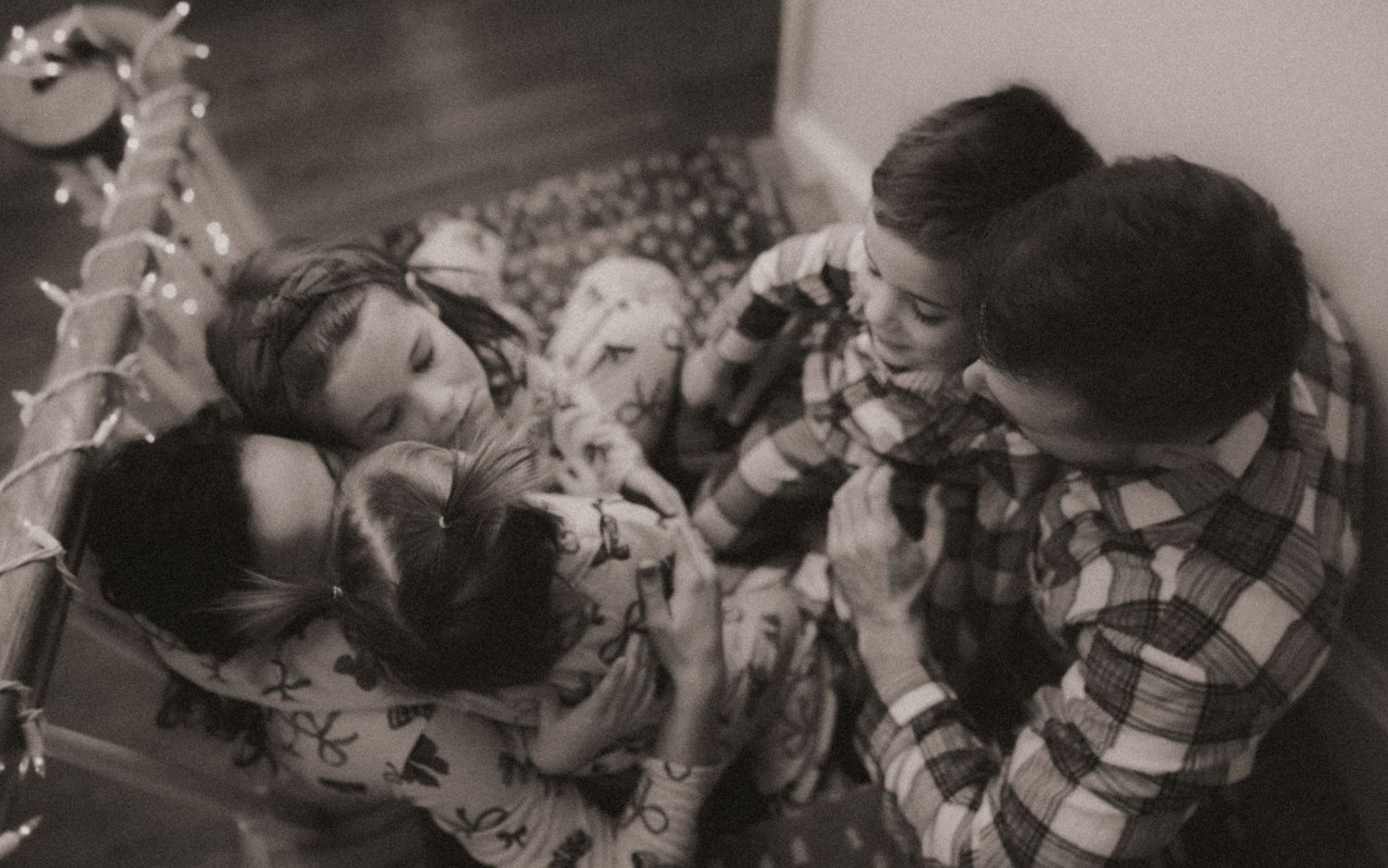 A vintage black and white photograph showing people relaxing and laughing together in a casual indoor setting.