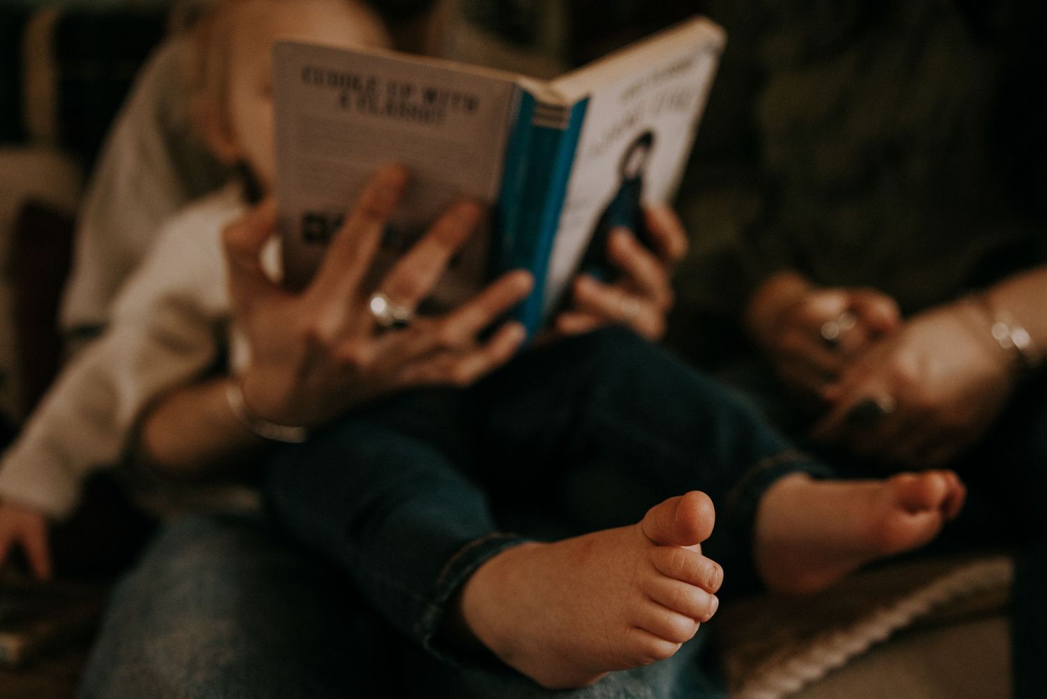 Close-up view of small bare feet while reading a book in a cozy setting.