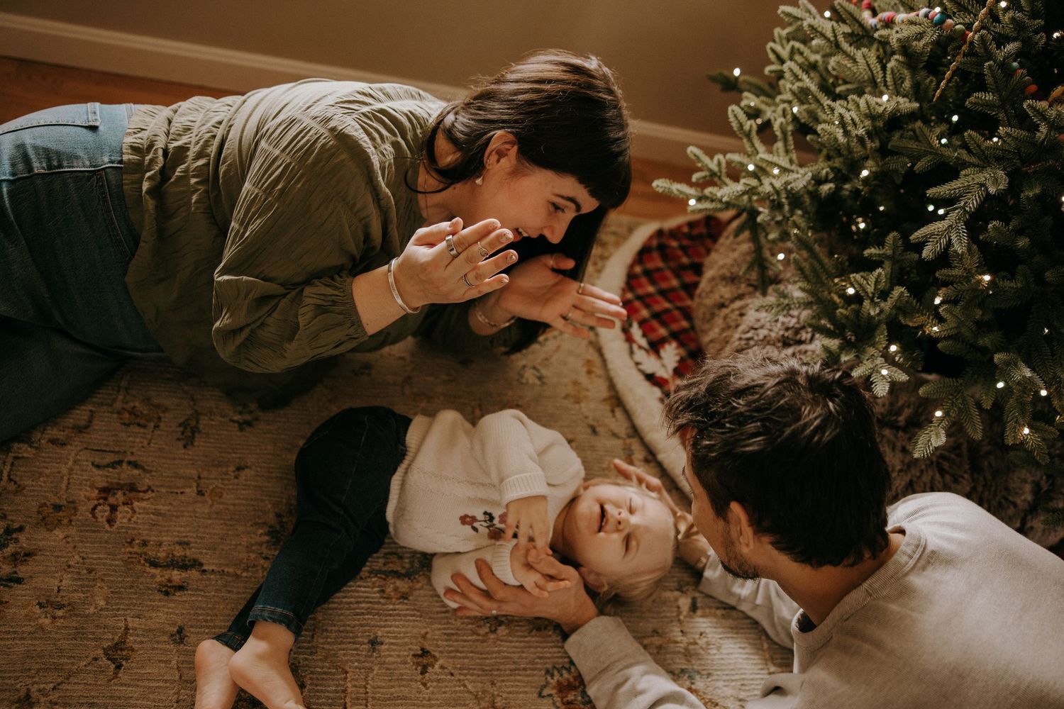 Couple sharing intimate moments while lying on bed with Christmas lights and decorations in warm ambient lighting.