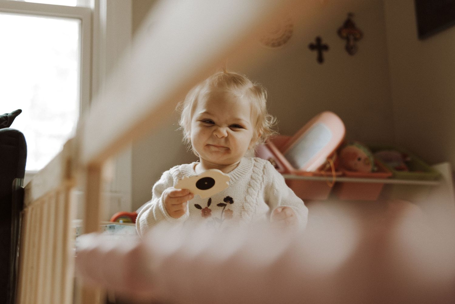 A toddler in a white bear-themed outfit sits in a warmly lit room with butterflies on the wall.