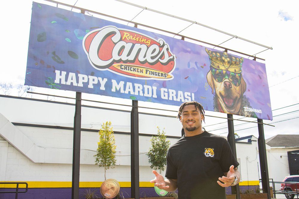 Raising Cane's restaurant exterior with Mardi Gras banner display.