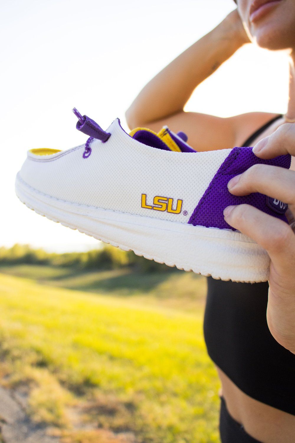 Close-up of white and purple LSU branded athletic shoe in sunlight.