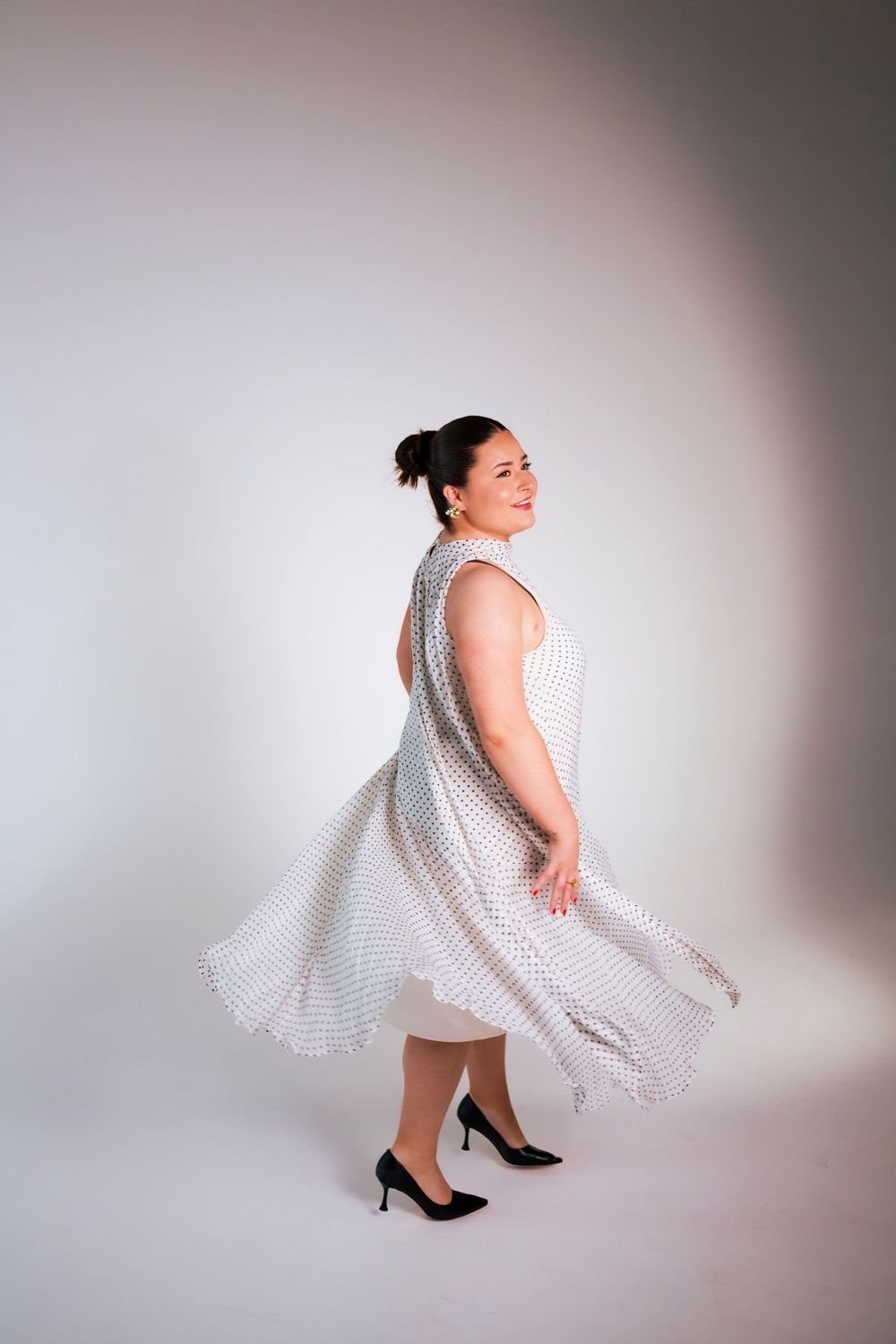 A figure in a flowing white dress spins gracefully in a sequence of dance-like movements against a light background.