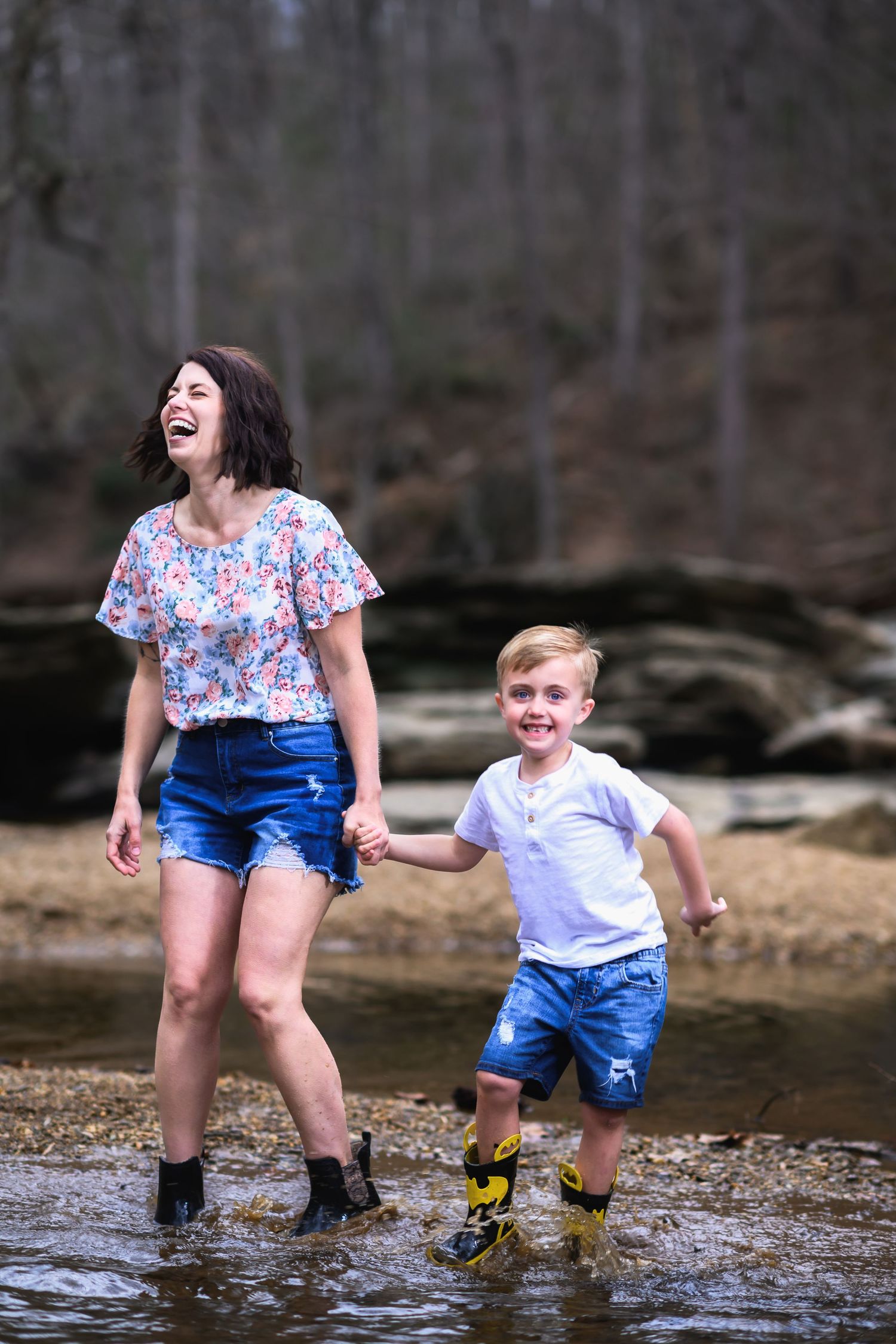 A pair wearing colorful clothing splash and laugh while playing in a shallow creek during a fun outdoor moment.