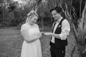 A couple shares a tender moment during their outdoor wedding ceremony in black and white.