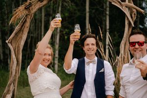 Celebratory group at an outdoor wedding venue raising their arms in joy during a summer celebration.