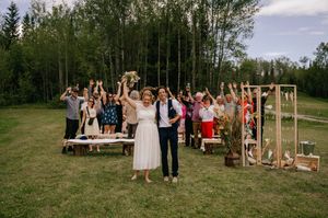 A beautiful outdoor wedding ceremony setup in a sunny meadow with wooden chairs and natural decor elements.