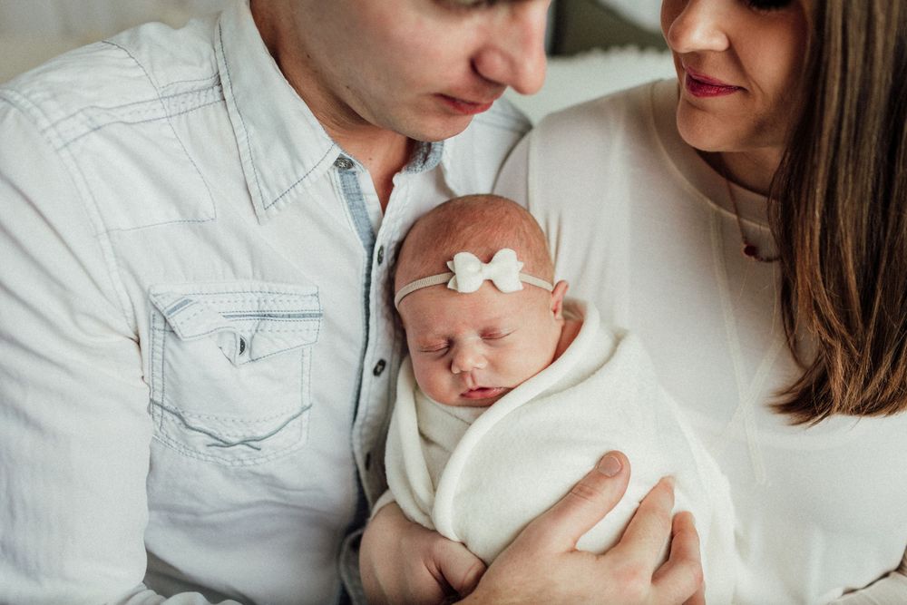 Tender family portraits in soft neutral tones showing parents bonding with their newborn.