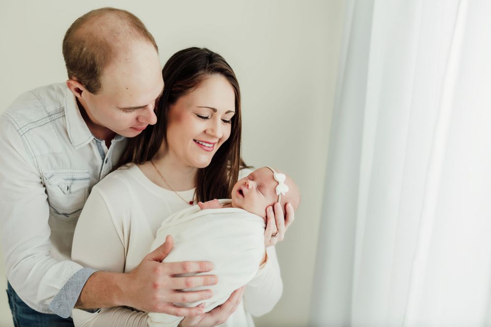 Sweet candid moments captured between parents and newborn in soft natural light.