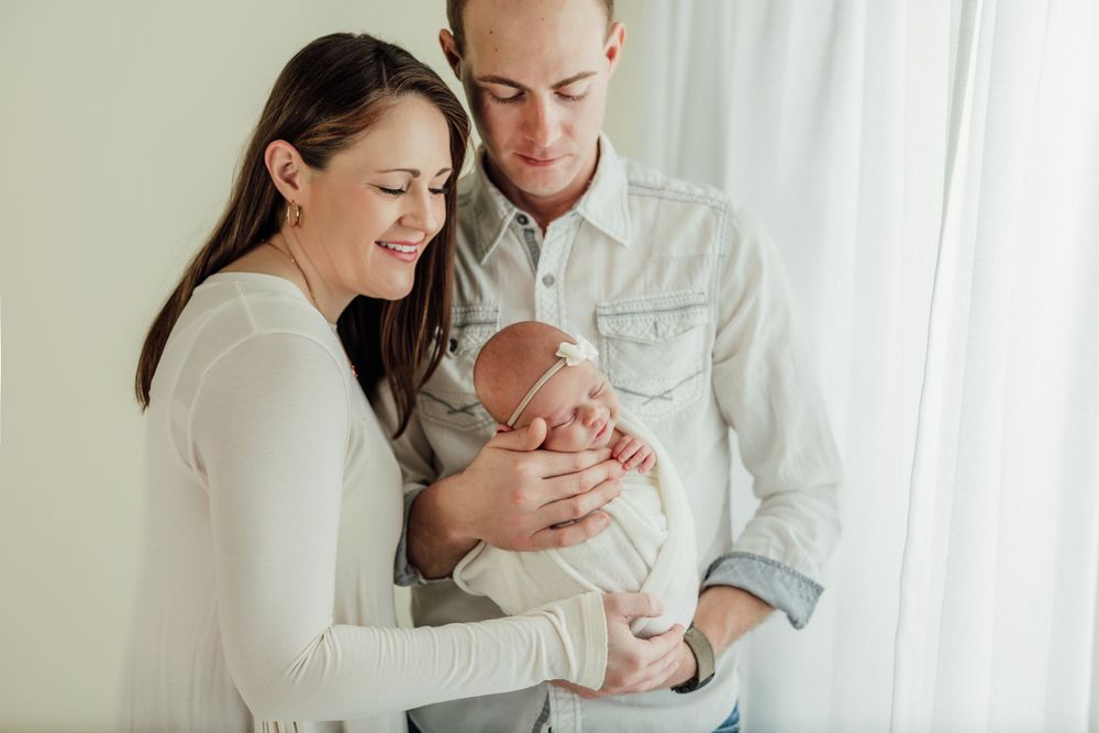 Lifestyle family session capturing loving moments with newborn in bright white setting.
