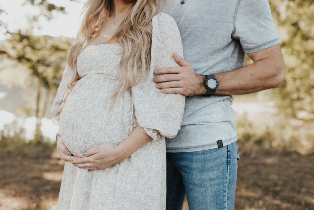 Tender maternity photo with couple in soft neutral tones highlighting a baby bump.
