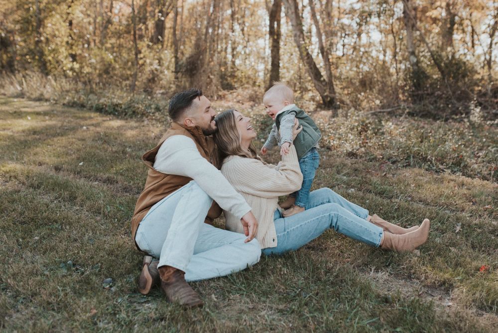 Romantic autumn photo of a couple relaxing together on grassy ground in casual attire.