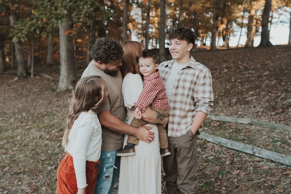 A tender family moment captured in warm autumn light near a wooden fence.