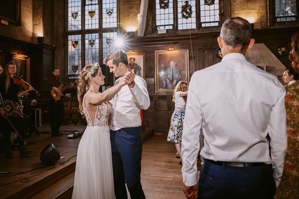 Guests dancing during wedding celebration in elegant hall with ornate windows and classical decor at Balliol College, Oxford