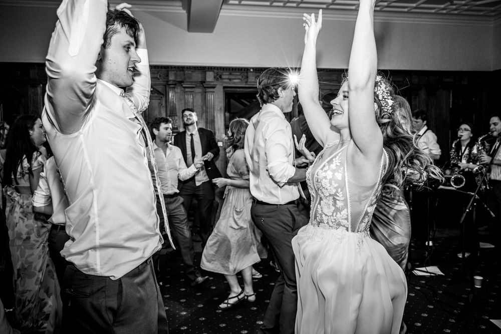 Black and white photo of celebration dancing at a wedding reception with guests in formal attire.