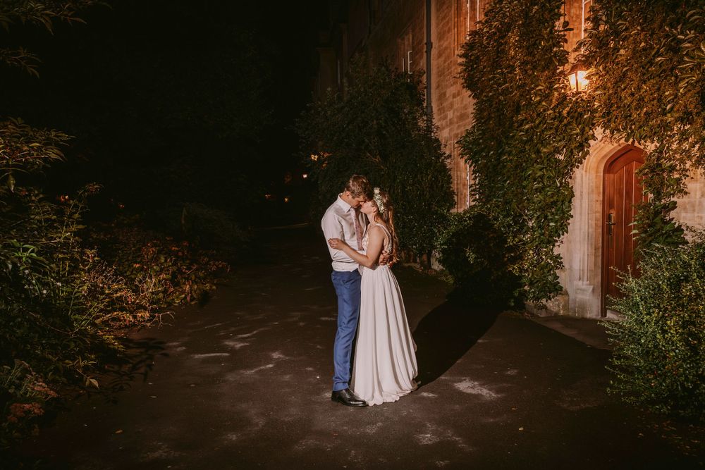 Intimate nighttime portrait of newlyweds against ivy-covered stone building at Balliol College, Oxford