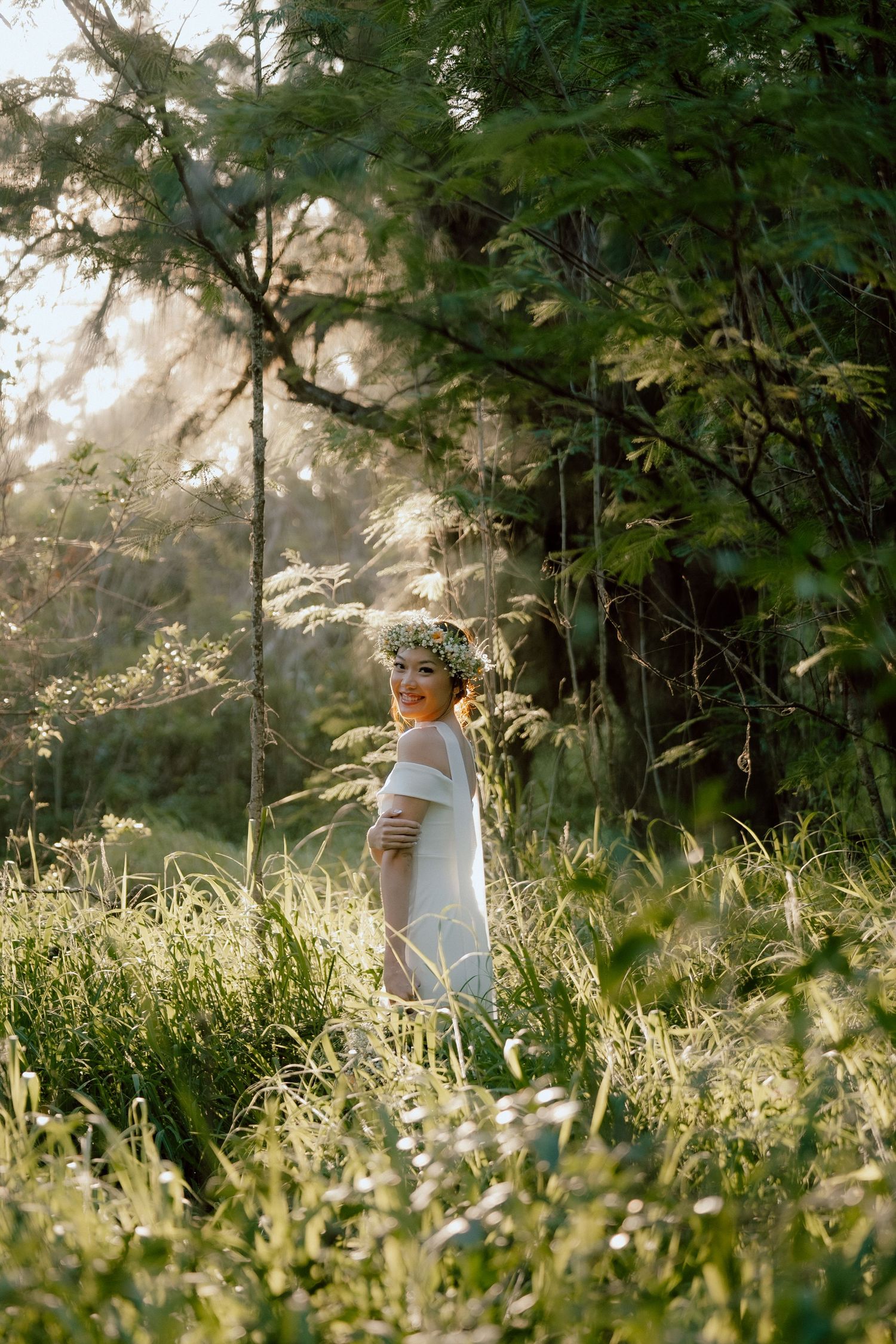 A figure stands in a sunlit meadow surrounded by lush greenery and tall grass during golden hour.