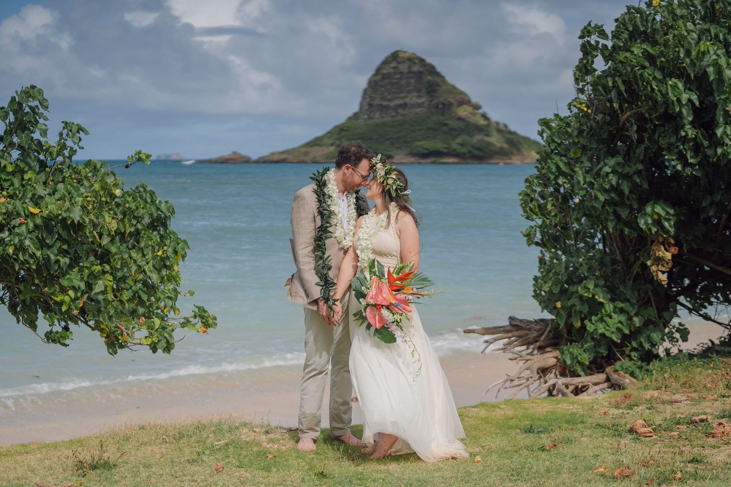 Tropical beach wedding ceremony setup with ocean views and mountain backdrop in Hawaii.