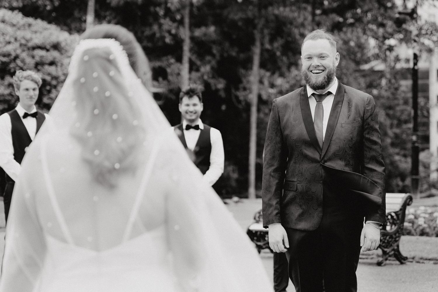 The First Look and a joyful moment between a veiled bride and smiling groom, captured by Apertured Media Auckland Wedding Photographer