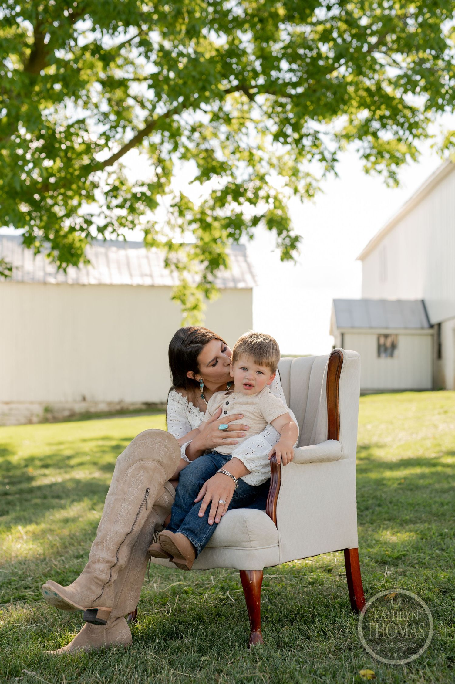 A touching outdoor portrait shows a parent and child bonding while sitting in an elegant white armchair.
