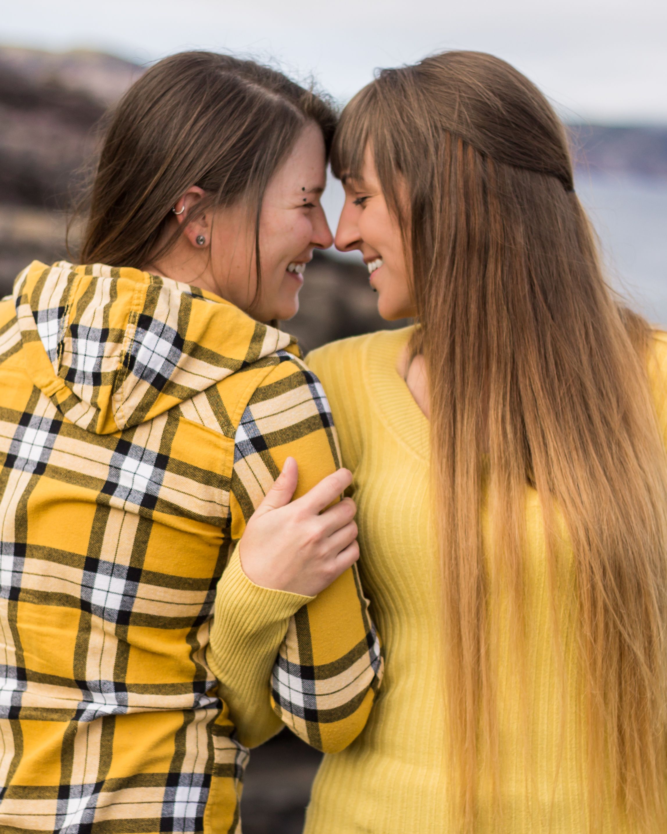 Two people in yellow clothing stand close together outdoors sharing an intimate moment.