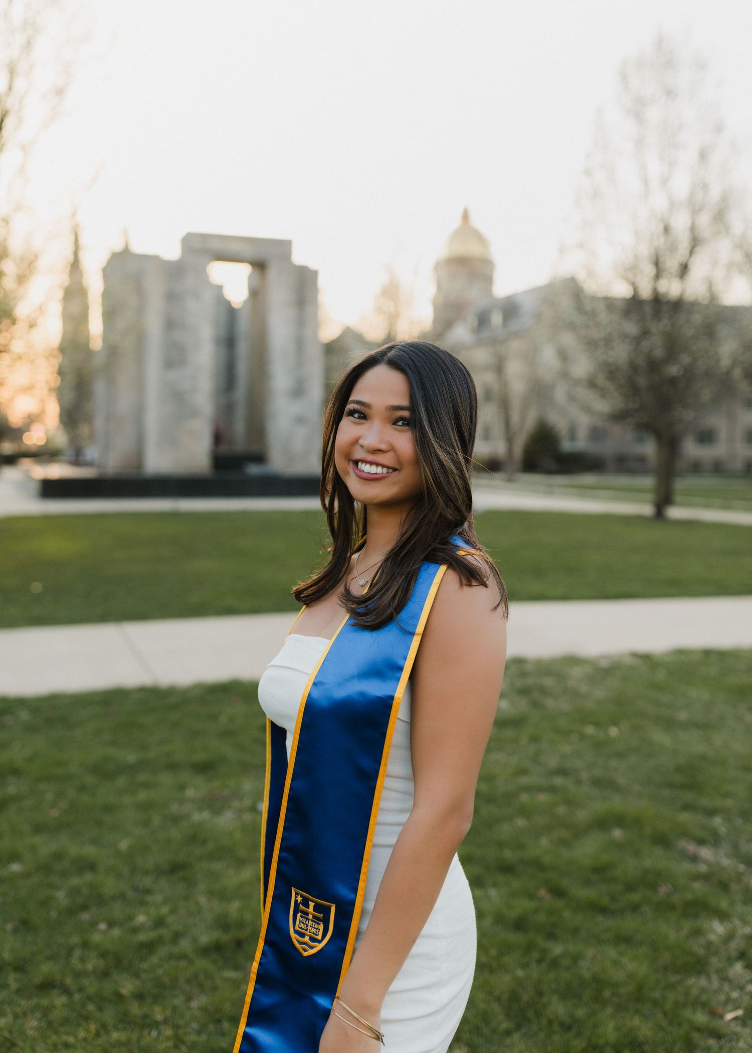 A graduation portrait taken on a university campus with iconic domed architecture in the background.