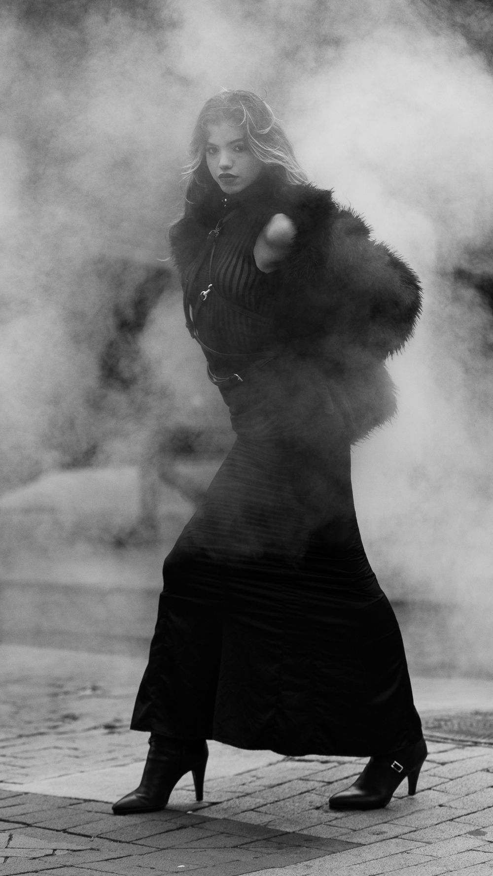 Model posing in black clothing with a smoky background that characterizes New York