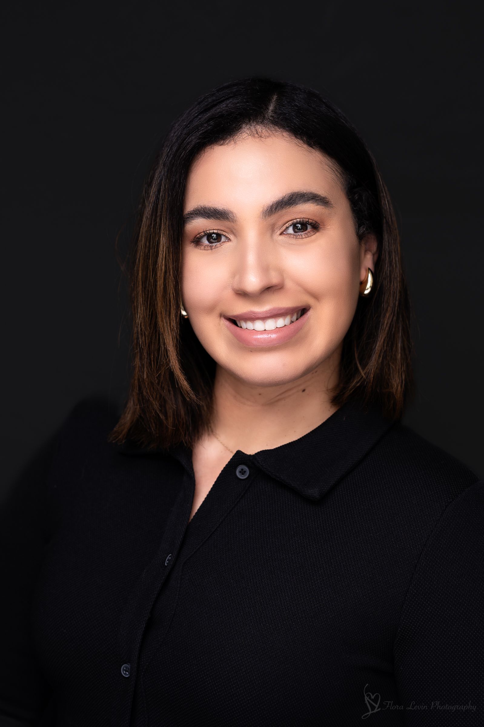 Professional studio portraits on black background showcase a warm smile and dark hair in a black collared shirt.