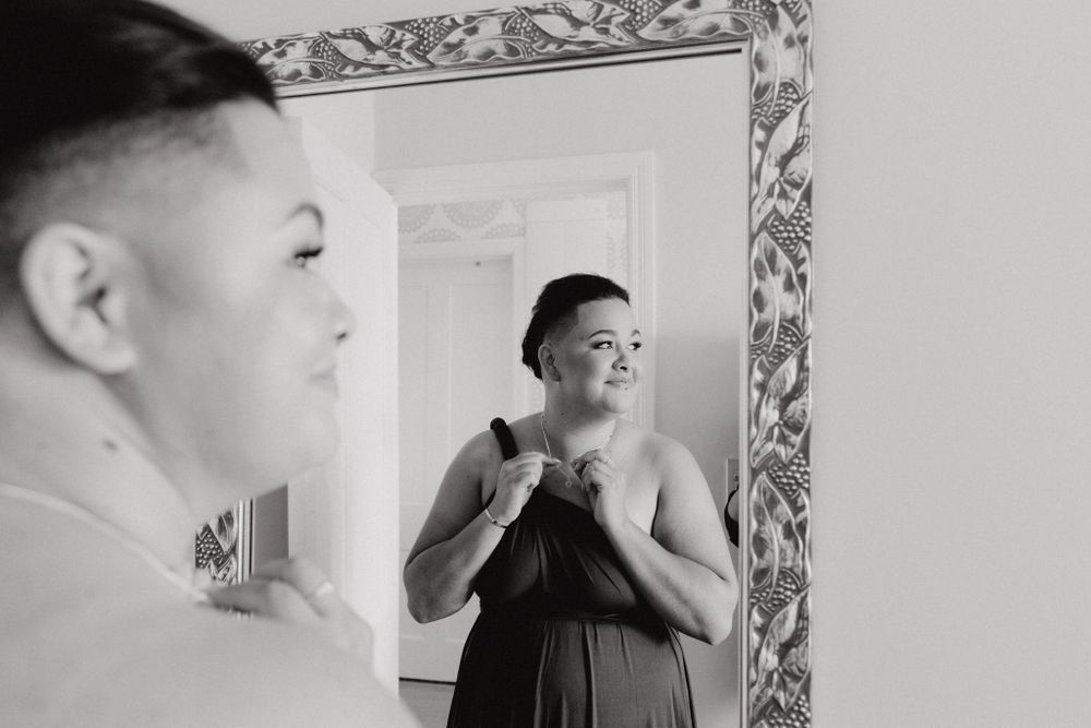 Reflection in mirror shows black and white portrait of a bridesmaid, captured by Apertured Media Auckland Wedding Photographer.