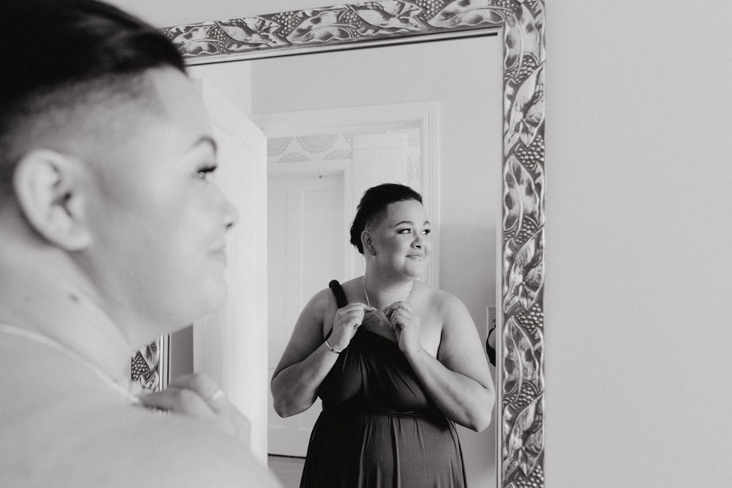 Reflection in mirror shows black and white portrait of a bridesmaid, captured by Apertured Media Auckland Wedding Photographer.