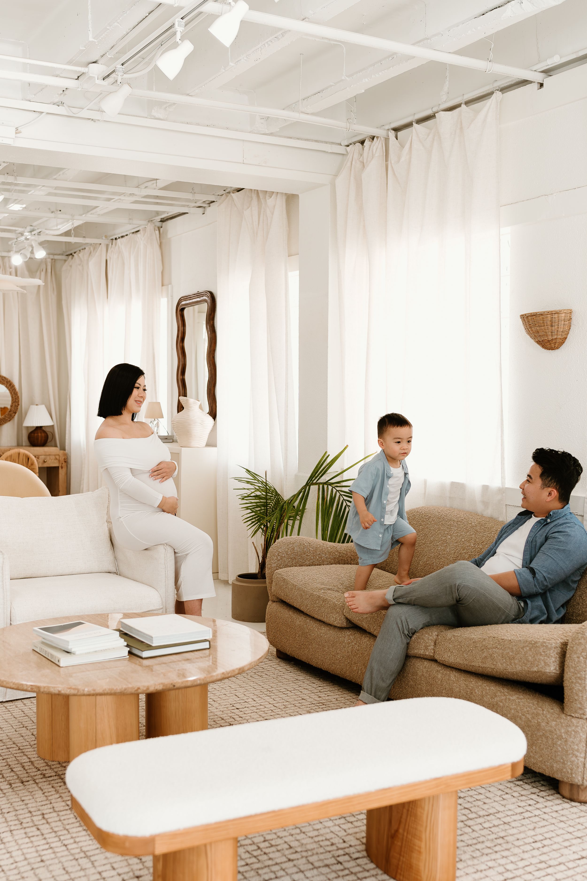 Family relaxing together on beige couch in bright white modern living room with coastal decor.