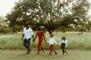 Family playing and running together through a scenic field during an outdoor photo session.