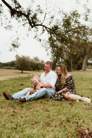 Family laying together on grass having fun during outdoor photo session.