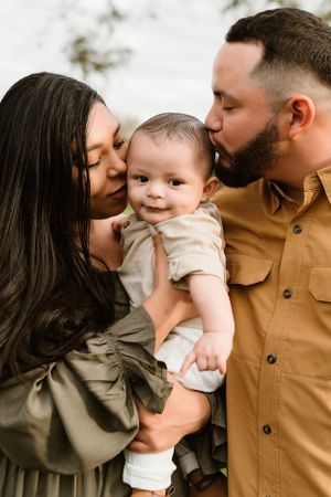 A family shares tender moments with their baby in neutral-toned clothing.
