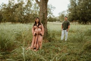Candid outdoor family photo session in a grassy field during golden hour.