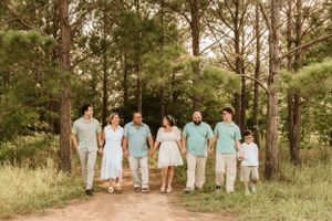 Family walking together through pine forest wearing coordinated pastel outfits.