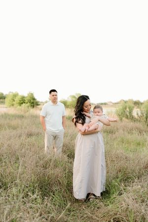 Couple in white outfits sharing tender moments in a sunlit field of tall grass.