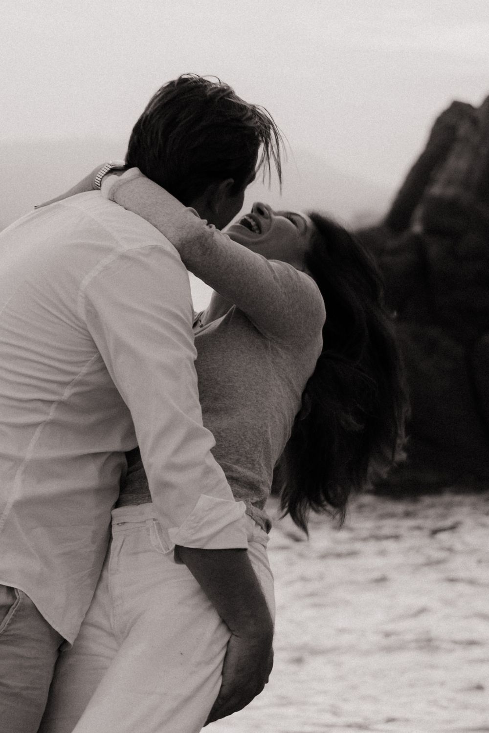 Un couple rigolent en dansant en bord de mer d'une image en noir et blanc.
