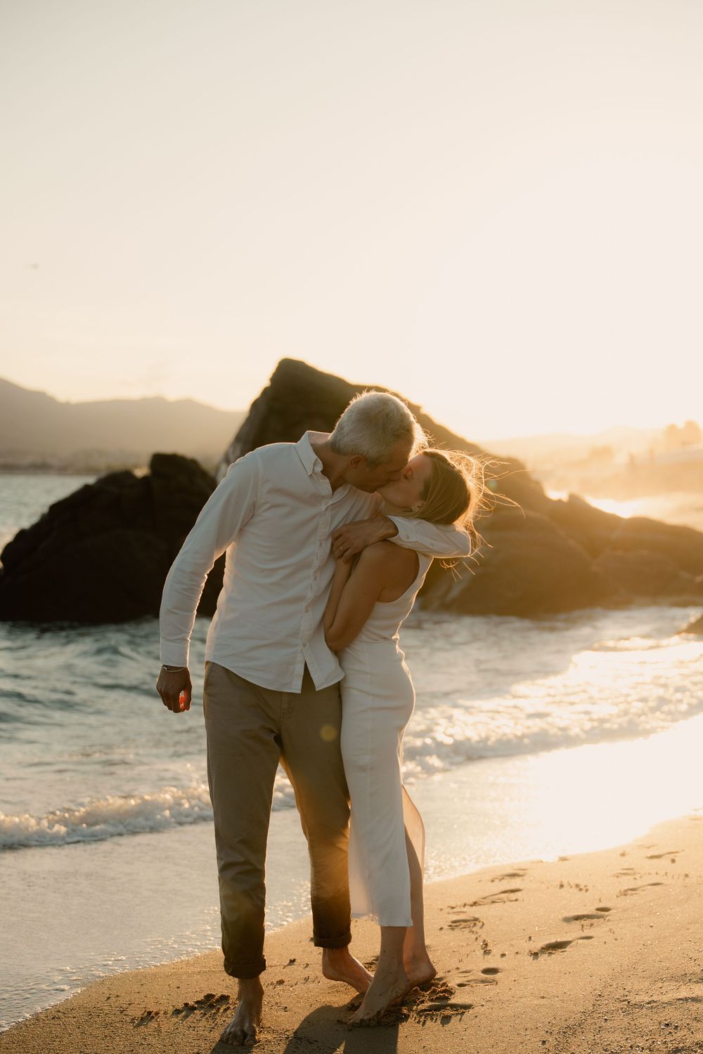 Un couple se promène sur une plage de sable au coucher du soleil, leurs silhouettes se détachant sur la lumière dorée à Cannes la Bocca.