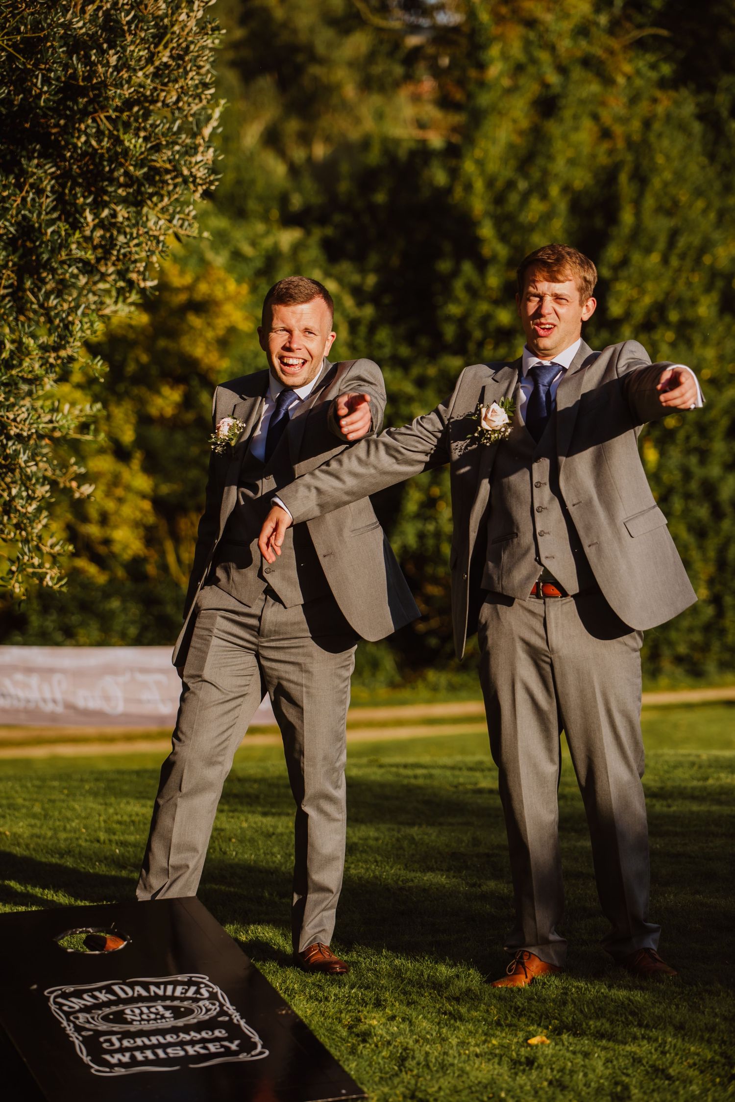 Grooms men are pointing and laughing playing garden games at Upwey House in Dorset. Dorset wedding games. Wedding venue Weymouth. .